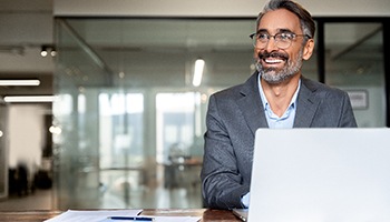 Man with glasses smiling while working in office